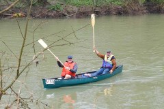 Two men in a canoe with paddles in the air