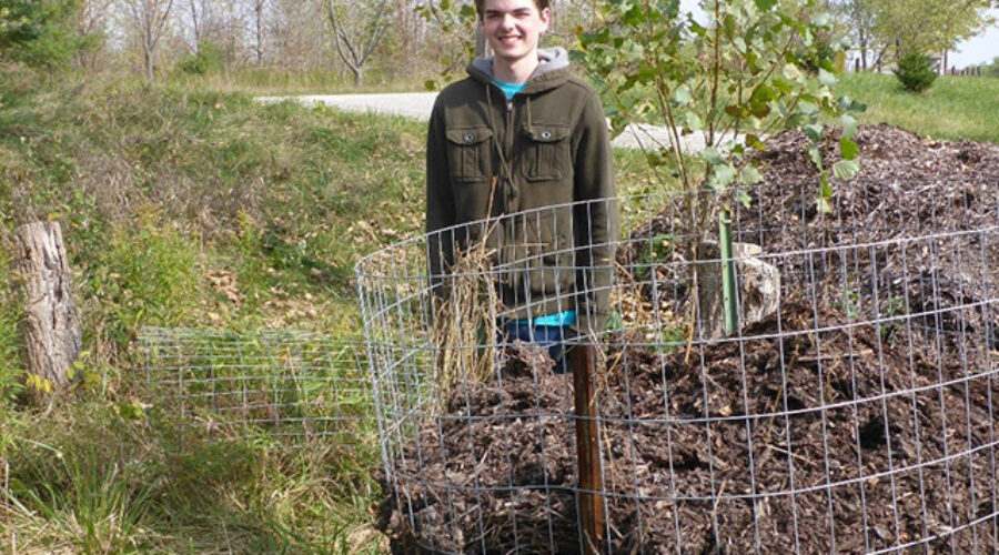 Brandon Jordan stands beside one of the Eastern Foxsnake artificial nesting boxes used to enhance the habitat for this endangered species