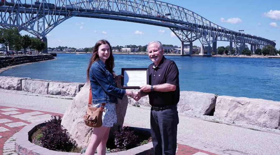 Heather Scott (left) is awarded with the Mary Jo Arnold Conservation Scholarship by St. Clair Region Conservation Authority Chair, Mike Stark (right) in front of the Bluewater Bridge in Sarnia..