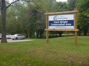 Clark Wright Conservation Area sign with trees and parking lot in the background