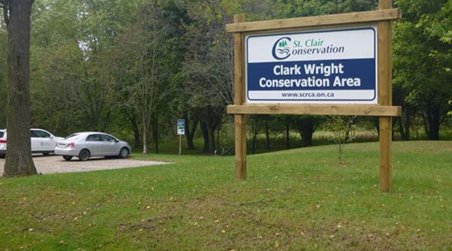 Clark Wright Conservation Area sign with trees and parking lot in the background