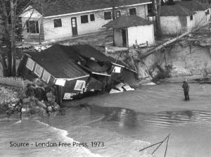House that has fallen into a riverbed with person looking at it