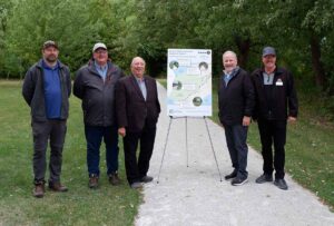 Five men standing on a trail beside a sign