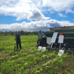 Two men standing in front of a tractor in a field on a sunny day.