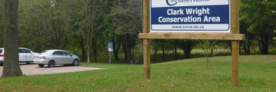 Clark Wright Conservation Area sign with trees and parking lot in background