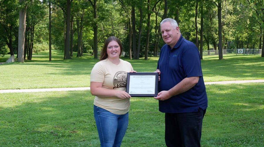 A woman and a man holding a frame in a forested area
