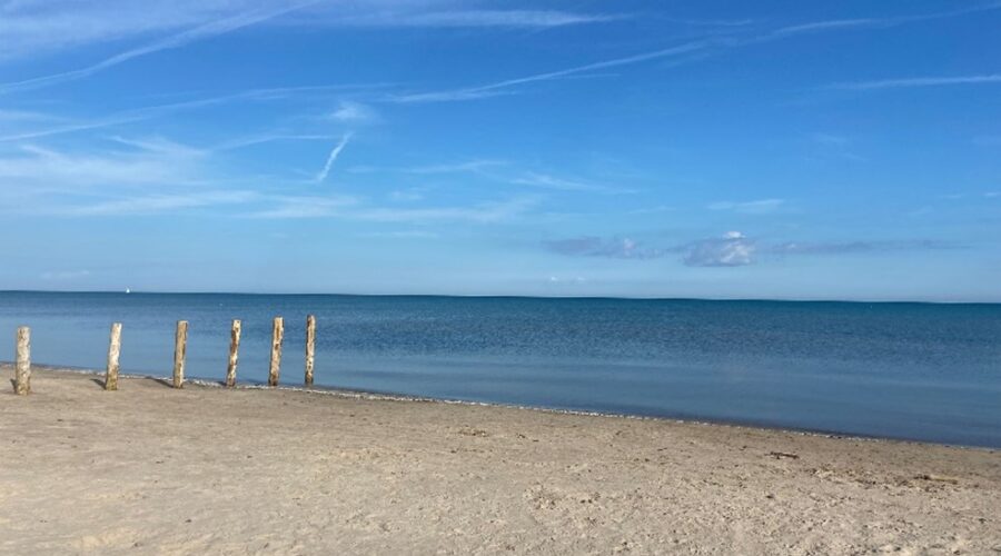 Sandy shoreline with blue water and sky