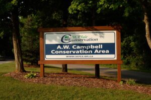 A.W. Campbell Conservation Area entrance sign with trees and grass.