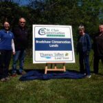 Four people standing beside the Bradshaw Conservation Lands sign