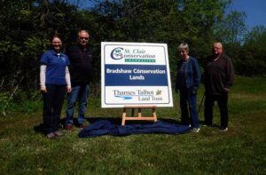 Four people standing beside the Bradshaw Conservation Lands sign